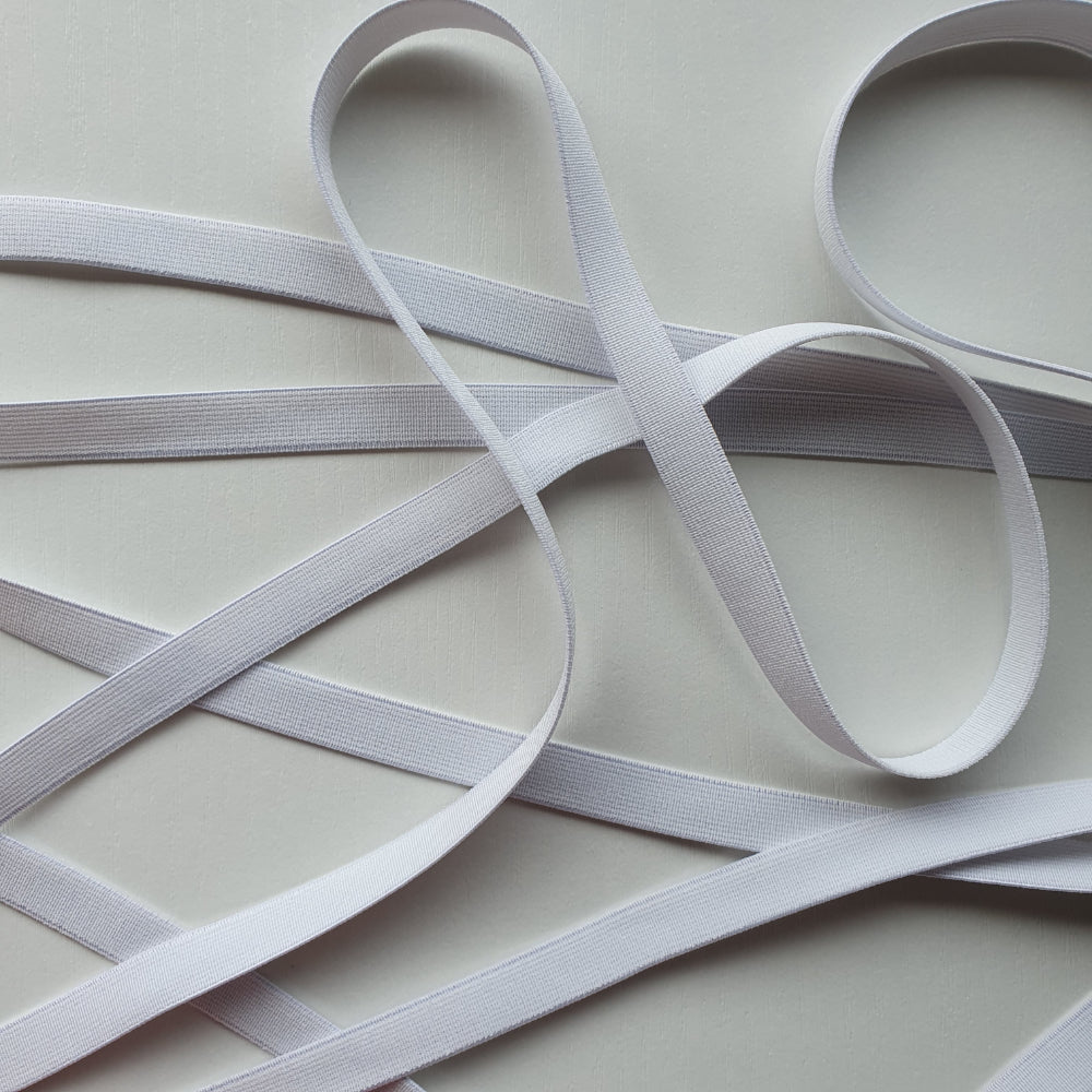 White elastic arranged in an overlapping crisscross pattern on a plain white background.