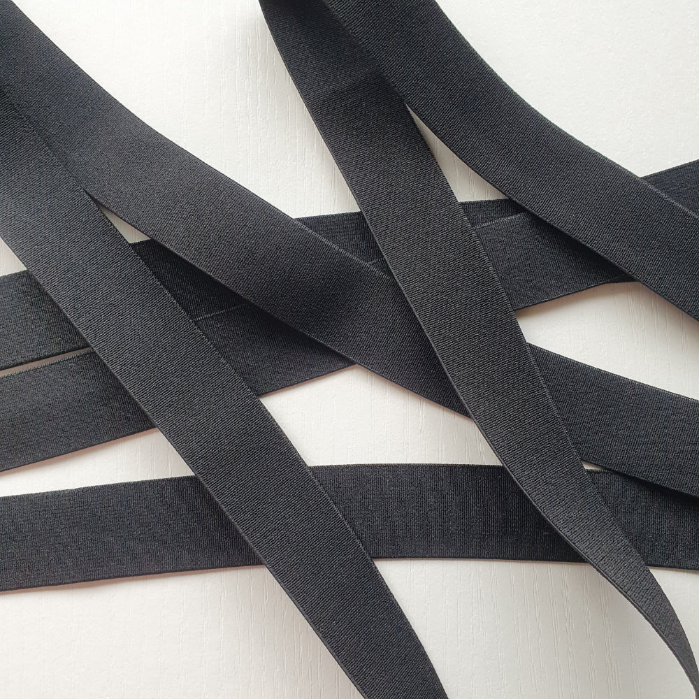 Black 25mm high density non-roll elastic arranged on a plain white background.